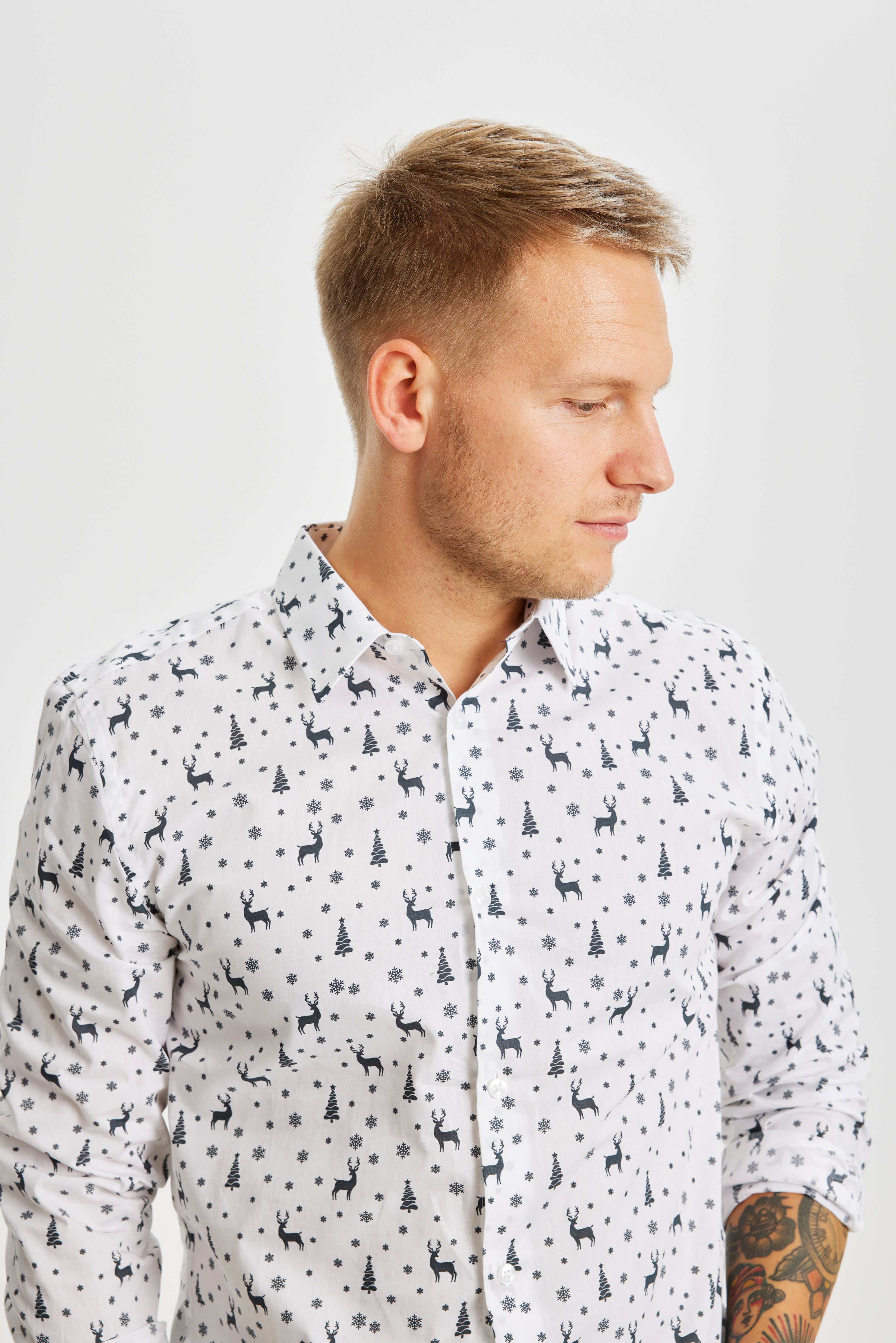 Un uomo che guarda di lato e indossa una camicia bianca di Natale.